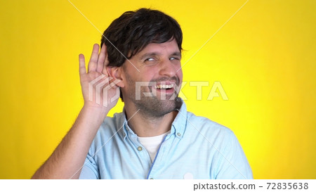 Fun man 30s years old isolated on yellow wall background studio. People sincere emotions lifestyle concept. Looking aside try to hear you with hand at ear overhears secrets 72835638
