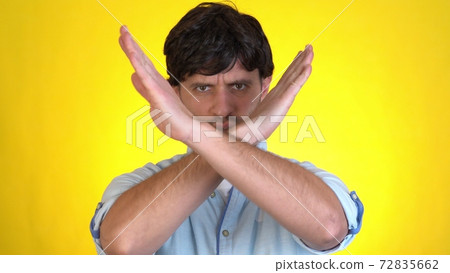 Displeased worried young man posing isolated on yellow background studio. Say no showing stop gesture with palm crossed hands Displeased worried young man posing isolated on yellow background studio. Say no showing stop gesture with palm crossed hands 72835662