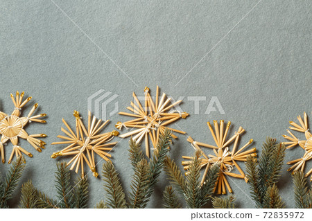 Handmade straw snowflakes and fir branches on a gray background. Horizontally with space. New year's layout with snowflakes 72835972