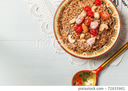spelt porridge with nuts, honey and candied fruits. in a ceramic bowl on a linen napkin with embroidery. lean, vegetarian dish spelt porridge with nuts, honey and candied fruits. in a ceramic bowl on a linen napkin with embroidery. lean, vegetarian dish 72835981