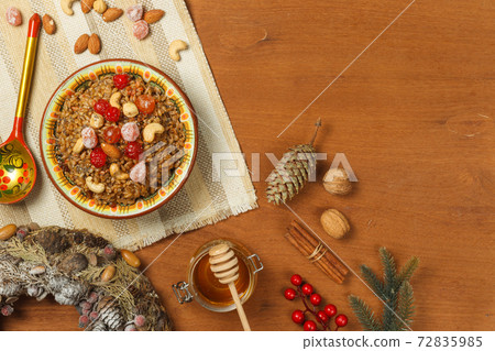 Kutia, a porridge made from wheat with nuts, poppy seeds, berries and dried fruits. On a wooden background with fir branches and cones. Top view with space Kutia, a porridge made from wheat with nuts, poppy seeds, berries and dried fruits. On a wooden background with fir branches and cones. Top view with space 72835985