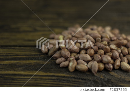 Raw peanuts on a rough wooden background. Raw peanuts on a rough wooden background. 72837263