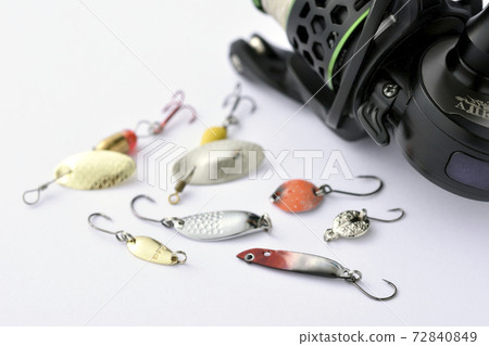 Spinning reel on the background of spinner and micrometal lure Spinning reel on the background of spinner and micrometal lure 72840849