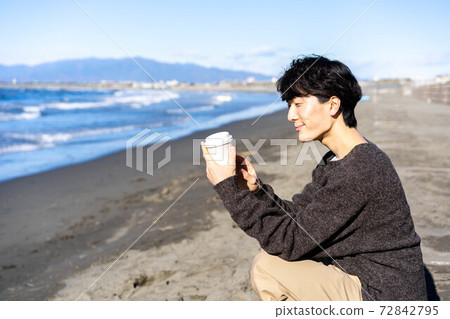 一個男人放鬆在他旅行目的地在海灘上的一杯咖啡 一個男人放鬆在他旅行目的地在海灘上的一杯咖啡 72842795