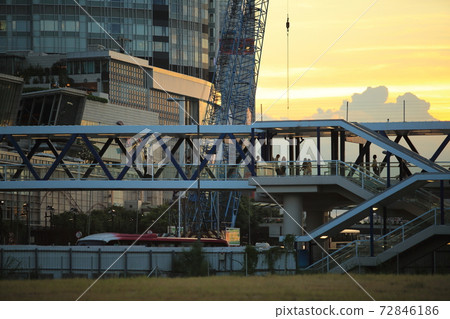 people pass through the busy footbridge to the ferry pier behind the IFC international finance center in Central, Hong Kong under the sunset 72846186