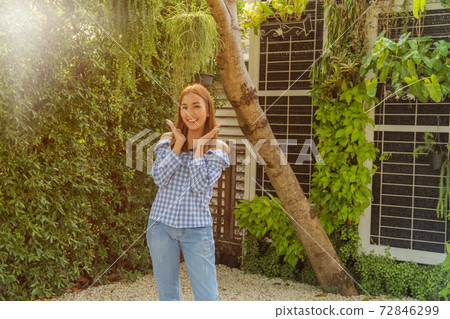 Happy smiling Asian beautiful young woman standing in the morning garden. 72846299