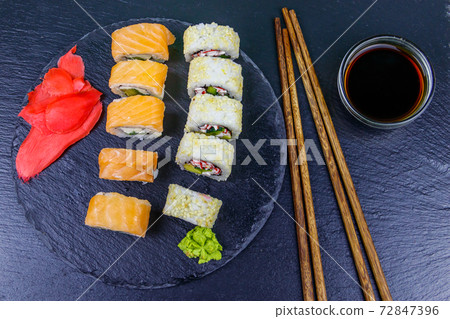 Set of sushi rolls on a black stone slate. Top view 72847396