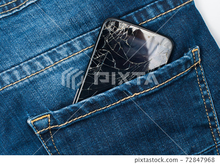 Mobile phone with a broken screen in the pocket of blue jeans. Mobile phone with a broken screen in the pocket of blue jeans. 72847968
