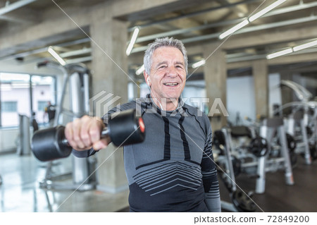 Losing weight and gainiong strength by a dumbell training performed by older man in the fitness center 72849200