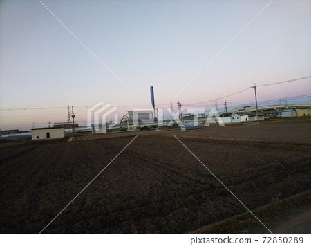 The scenery of the fields where you can see the power lines in the distance, and the junction of the highway in the distance. The dusk sky dyed pink in the background The scenery of the fields where you can see the power lines in the distance, and the junction of the highway in the distance. The dusk sky dyed pink in the background 72850289