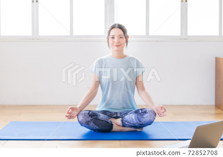 Young woman doing yoga online in the living room Young woman doing yoga online in the living room 72852708