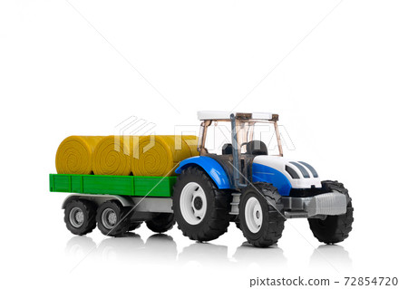 farm tractor toy with hay trailer, isolated on white farm tractor toy with hay trailer, isolated on white 72854720