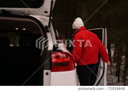 White car in winter forest. The woman in red opens the door White car in winter forest. The woman in red opens the door 72858648