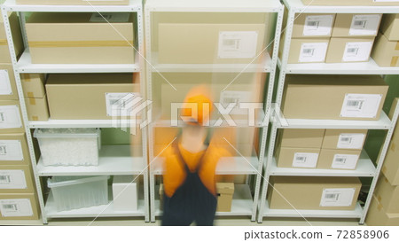 Warehouse worker sorting boxes on the shelves, long exposure motion blur shot Warehouse worker sorting boxes on the shelves, long exposure motion blur shot 72858906