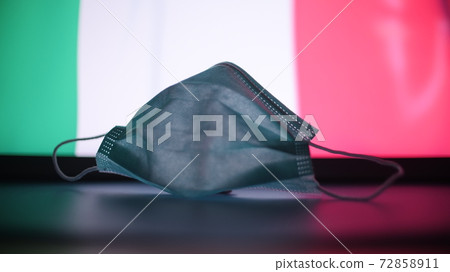Disposable mask at blurred flag of Italy. Italian COVID-19 outbreak concept 72858911