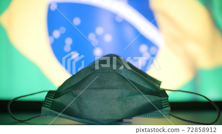 Medical mask at blurred flag of Brazil. Pandemic concept Medical mask at blurred flag of Brazil. Pandemic concept 72858912