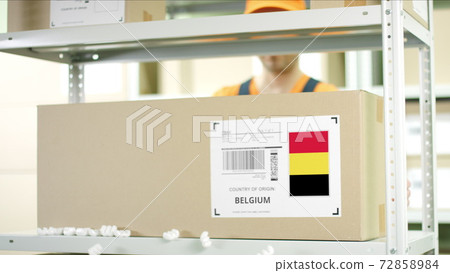 Warehouse worker puts a carton with goods from Belgium 72858984