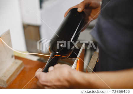 A man processes a bottle into a glass 72866493