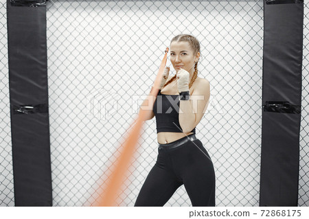 Portrait of a confident young woman in boxing gloves Portrait of a confident young woman in boxing gloves 72868175