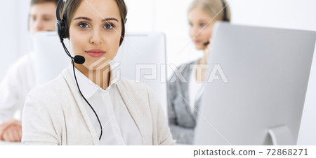 Call center. Group of diverse operators at work. Beautiful woman in headset communicating with customers of telemarketing service. Business concept Call center. Group of diverse operators at work. Beautiful woman in headset communicating with customers of telemarketing service. Business concept 72868271