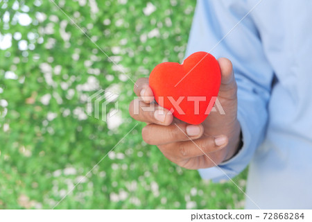 man holding red heart on green background man holding red heart on green background 72868284