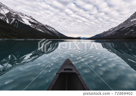 Canoeing with cloudy reflection on Maligne Lake in Rocky Mountains at Jasper national park 72869402