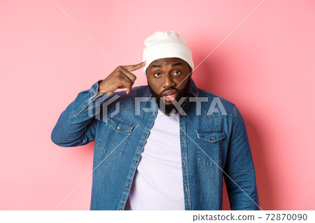 Annoyed and pissed-off african-american man pointing finger at head, scolding someone stupid, staring bothered at camera, pink background Annoyed and pissed-off african-american man pointing finger at head, scolding someone stupid, staring bothered at camera, pink background 72870090