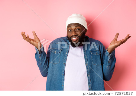 Unsure Black guy shrugging and looking confused at camera, dont know, standing indecisive against pink background Unsure Black guy shrugging and looking confused at camera, dont know, standing indecisive against pink background 72871037
