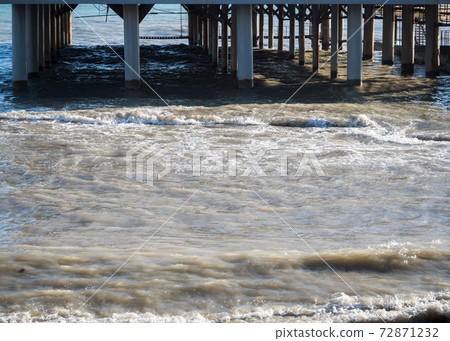 Sea pier with columns on the beach 72871232