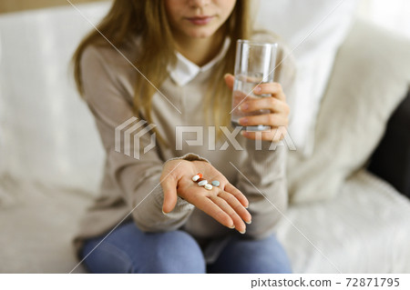 Close-up woman holding pills time to take medications, cure for headache, high blood pressure or cholesterol level remedy pain killer drugs. Stay at home concept during Coronavirus pandemic and self Close-up woman holding pills time to take medications, cure for headache, high blood pressure or cholesterol level remedy pain killer drugs. Stay at home concept during Coronavirus pandemic and self 72871795