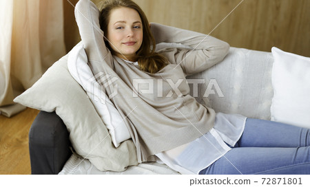 Happy blond woman put hands behind head sitting leaned on couch caucasian female enjoy lazy weekend or vacation in sunny living room Happy blond woman put hands behind head sitting leaned on couch caucasian female enjoy lazy weekend or vacation in sunny living room 72871801