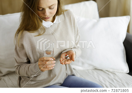 Close-up woman holding pills time to take medications, cure for headache, high blood pressure pain killer drugs at home. Stay at home concept during Coronavirus pandemic 72871805