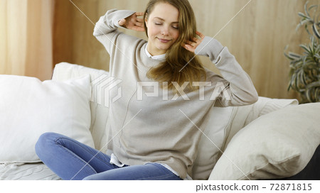 Happy brunette woman put hands behind head sitting leaned on couch, european female stretching and enjoying lazy weekend or vacation in cozy living room Happy brunette woman put hands behind head sitting leaned on couch, european female stretching and enjoying lazy weekend or vacation in cozy living room 72871815