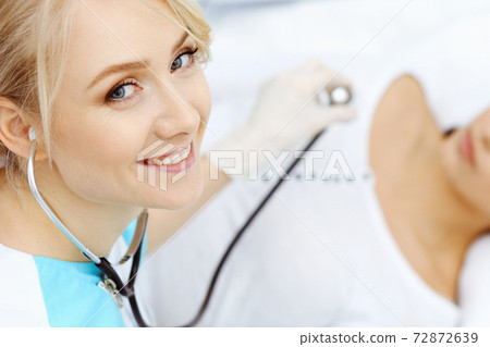 Female doctor and young woman patient in hospital. Physicians examine girl lying at the bed, view from above 72872639