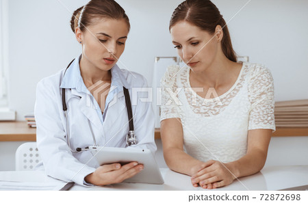 Doctor and patient are sitting and discussing health examination results while using tablet computer. Health care, medicine and good news concepts Doctor and patient are sitting and discussing health examination results while using tablet computer. Health care, medicine and good news concepts 72872698
