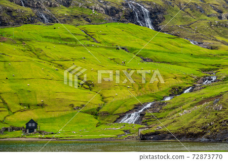Waterfall, lake and house under the hill 72873770