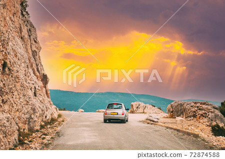 Verdon, France. Small car on road on background of French mountain nature landscape the Gorges Du Verdon in France. Altered Sunset Sky 72874588