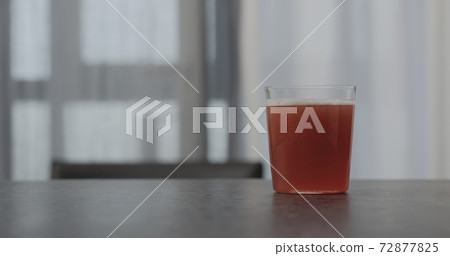 pink fizzy drink in a tumbler glass on concrete countertop with window on background 72877825