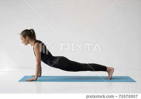 Young woman practicing yoga, lying and stretching in Cobra pose, doing Bhujangasana exercise. Attractive girl in black sportswear. Beautiful sporty fit yogini woman practices yoga asana bhujangasana. Young woman practicing yoga, lying and stretching in Cobra pose, doing Bhujangasana exercise. Attractive girl in black sportswear. Beautiful sporty fit yogini woman practices yoga asana bhujangasana. 72878807