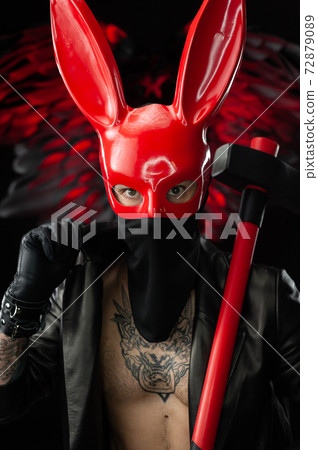 a man in a red rabbit mask in a leather cloak with an axe 72879089