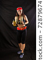 Beautiful girl in jogging red uniform, drinks water after training in the studio on a black background 72879674