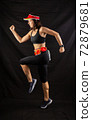 girl in red jogging uniform runs in the studio on a black background 72879681
