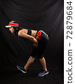 Beautiful girl in a jogging red uniform warming up before training in the studio on a black background 72879684