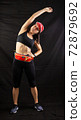 Beautiful girl in a jogging red uniform warming up before training in the studio on a black background 72879692