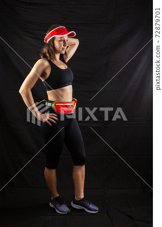 Beautiful redhead girl in jogging uniform posing in studio on black background 72879701