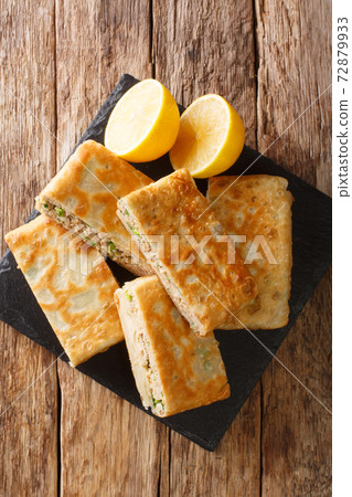Murtabak is a stuffed pancake or pan-fried bread with meat, egg and green onion closeup in the board. vertical top view 72879933