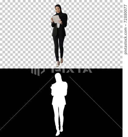 Arabian businesswoman in hijab using tablet computer while walki 72880077