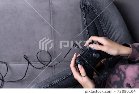 Woman in pink hoodie with manicured hands hold gamepad Woman in pink hoodie with manicured hands hold gamepad 72880104