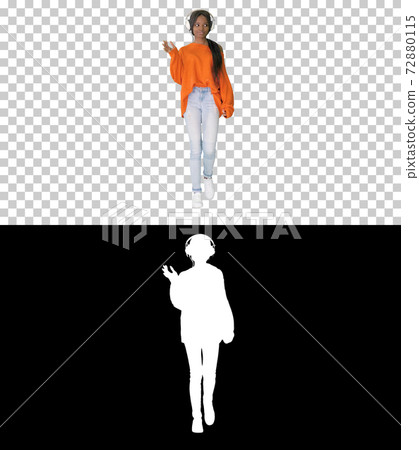 Smiling african american woman with headphones walking listening Smiling african american woman with headphones walking listening 72880115