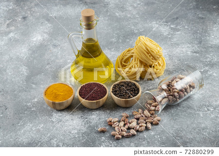 A glass jar with raw white kidney beans and raw nest pasta on a gray background 72880299